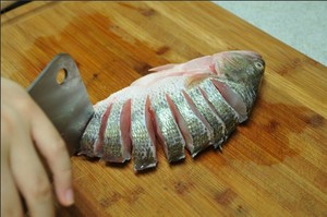 將鱸魚清洗干凈，從脊椎處切斷至腹部，腹部保留1cm左右不要切斷。