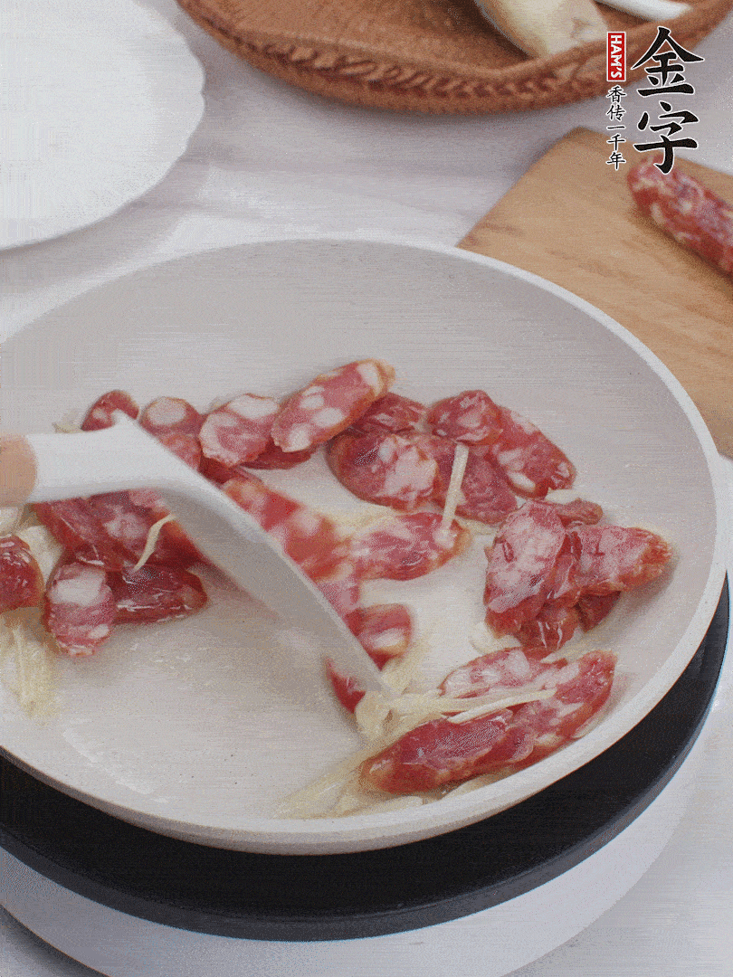 油溫3成熱時(shí)，下姜絲、蒜片、香腸炒出油脂。