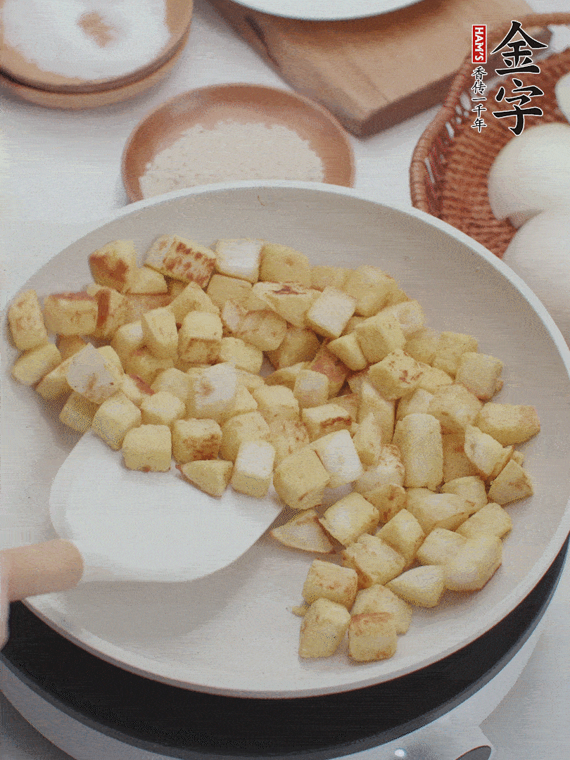起鍋熱油，倒入饅頭丁，小火煎至蛋液凝固定型再翻面，饅頭丁部煎至金黃時(shí)盛起待用。
